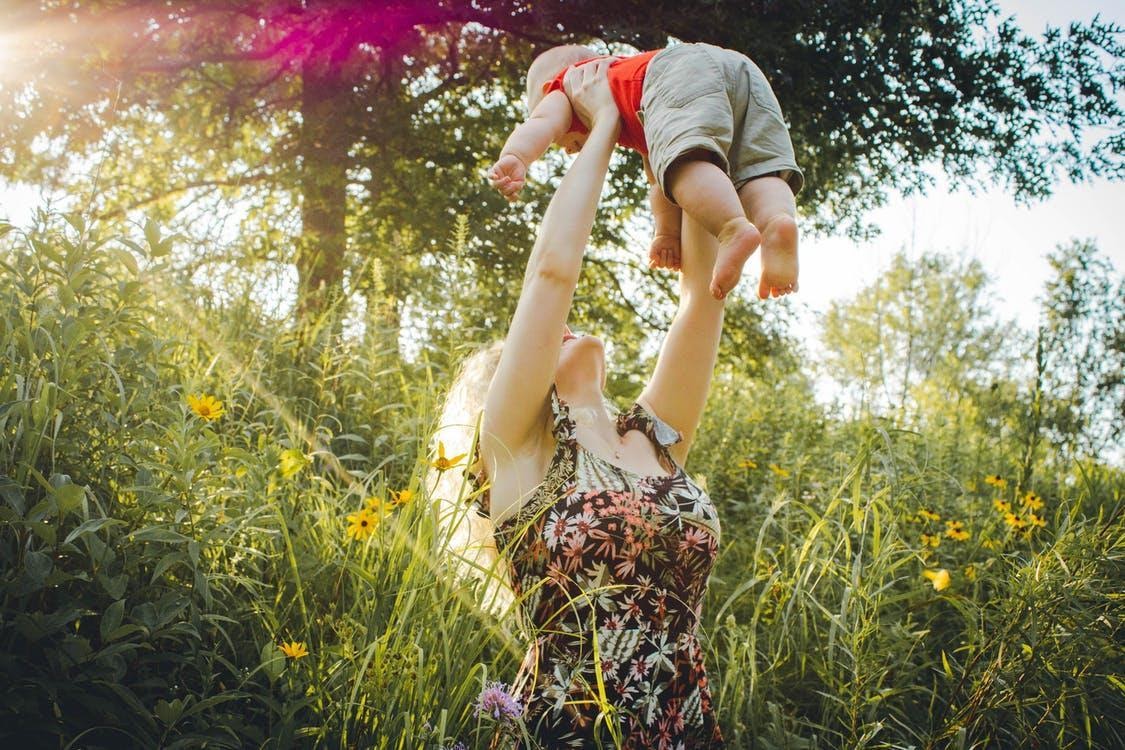 Woman Carrying Baby Near Grass